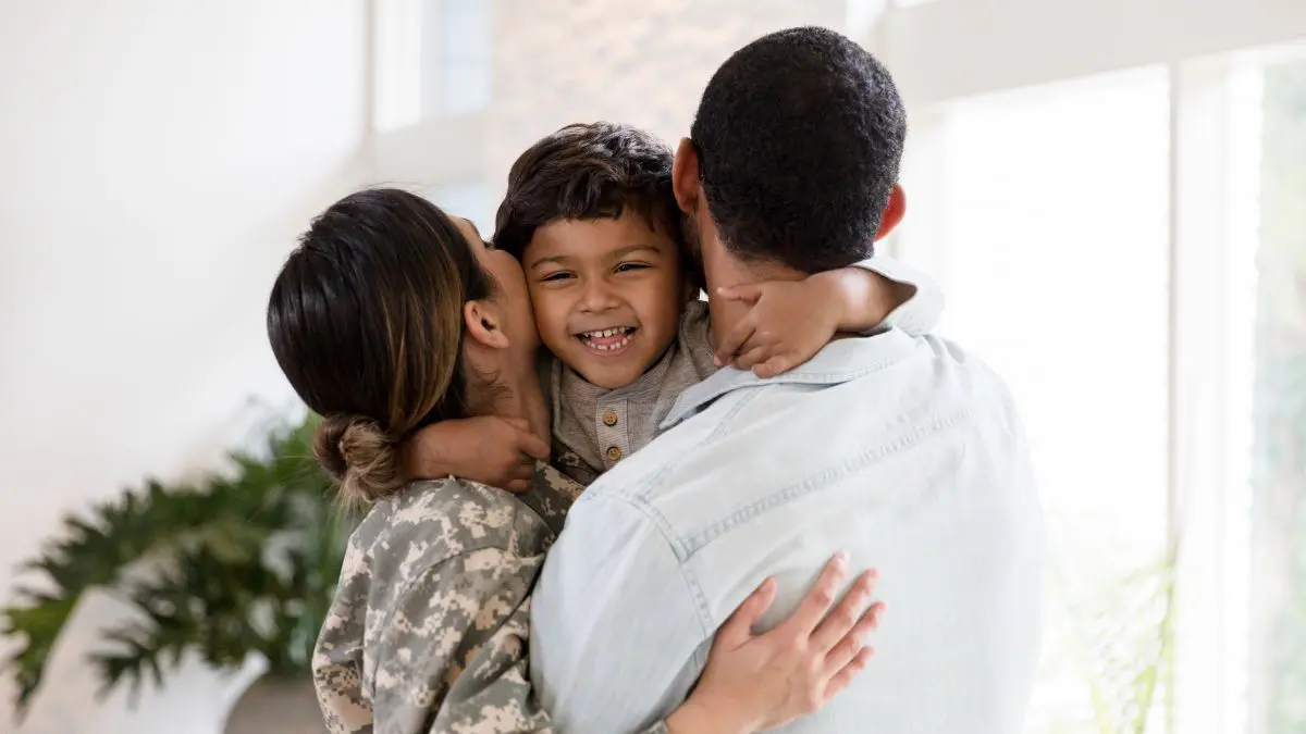 Mother in military uniform and father facing away hugging son