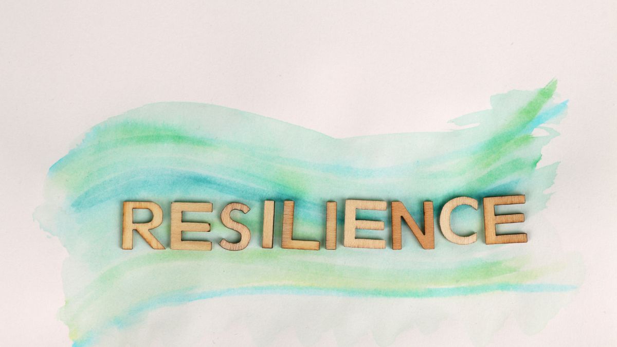 The word Resilience in gold on a green watercolor background