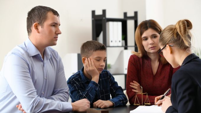 Mother and Father with son talking to a teacher at a parent teacher conference