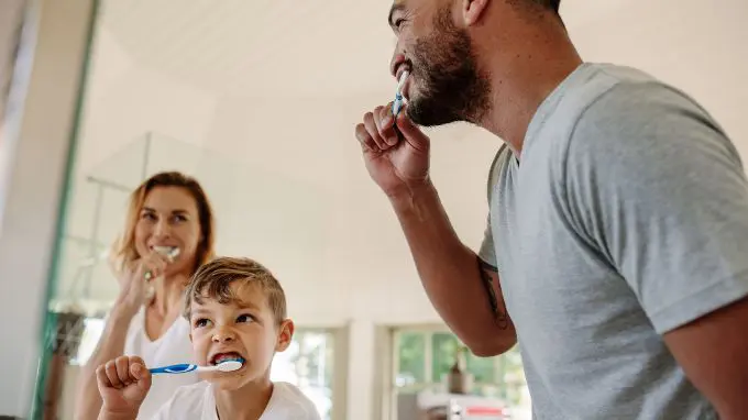 Mixed race family, mother, father, and son, brushing teeth together
