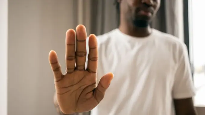 Black man holding one hand up in a "stop" motion